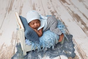 Baby crawls and explores a rustic white wooden floor, wearing a light blue outfit.