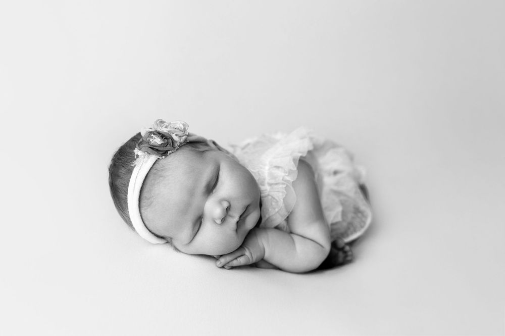 An artistic collage of 4 peaceful newborn photographs showing infants sleeping in different serene poses.