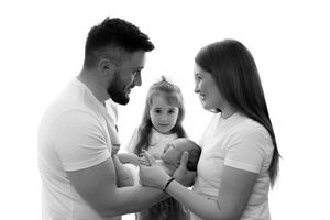 A black and white portrait of a loving family wearing white t-shirts while sharing a tender moment together.