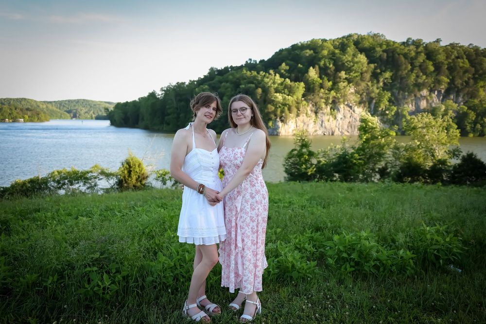 Scenic outdoor photoshoot with rolling hills and lake views in the background.