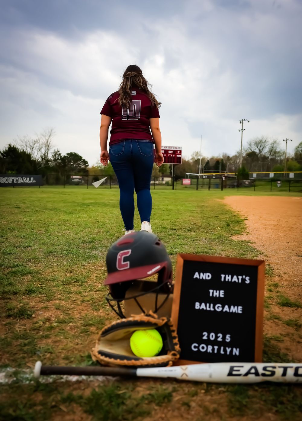 Softball themed photo series with equipment and custom signs on a dirt field.