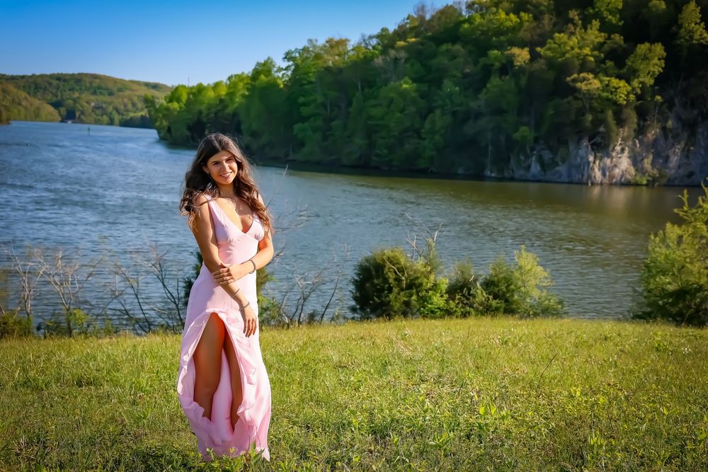 Scenic outdoor portraits with river cliffs and green hills in the background.
