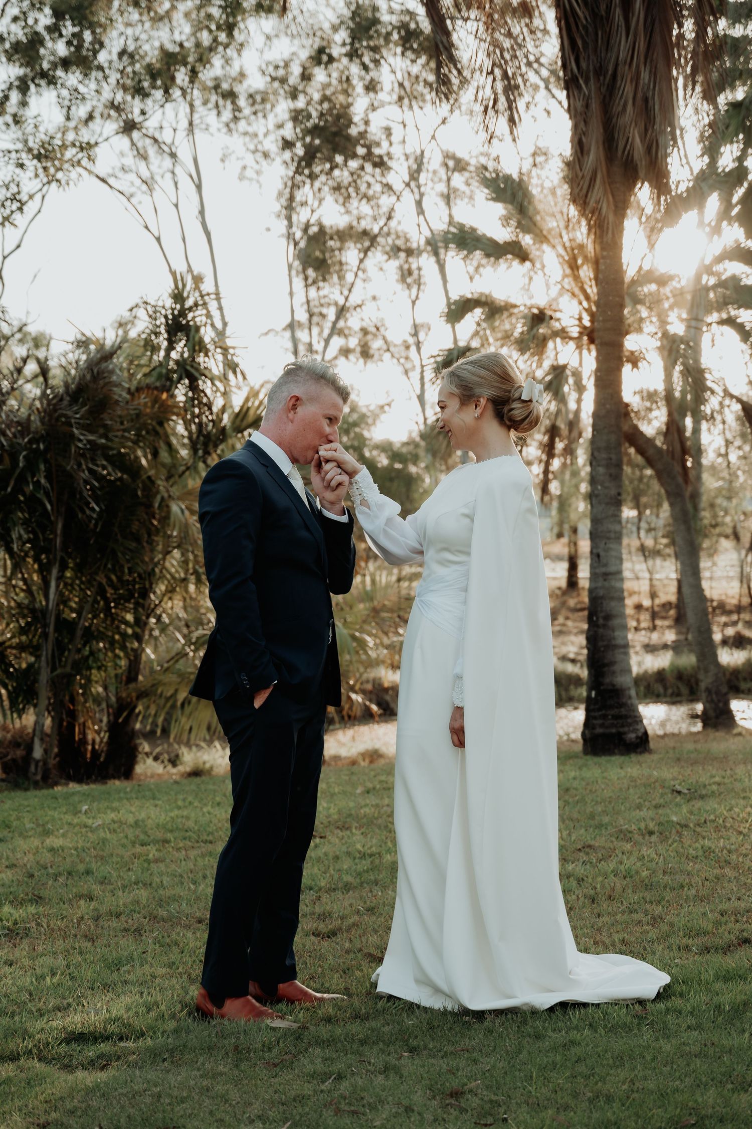 Tender wedding moment captured between couple in sunlit gladstone garden setting.