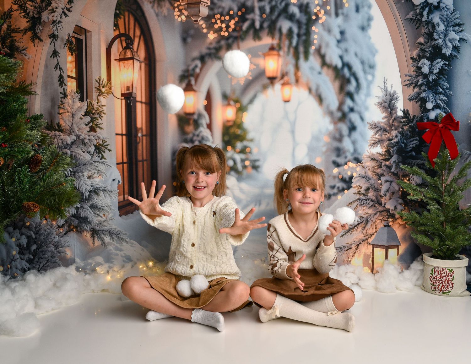 Christmas Mini Birmingham — Two girls playing with snowballs in front of a snowy city arch during a Christmas Mini photo session.