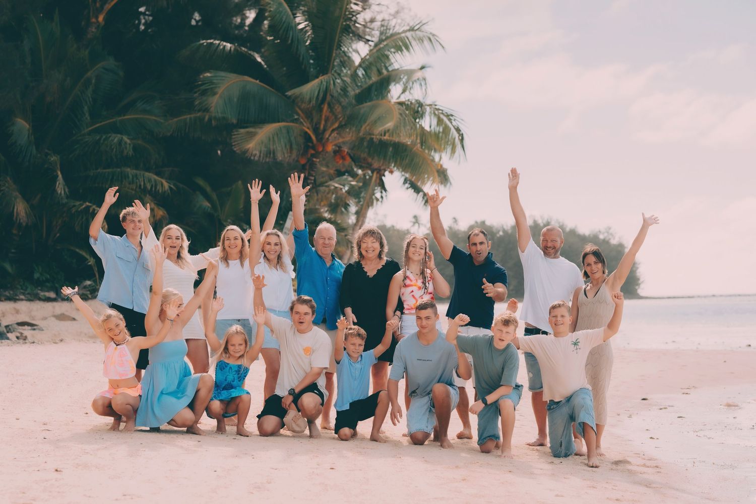 Group in coordinating pink and white outfits poses on black volcanic rocks by the ocean.