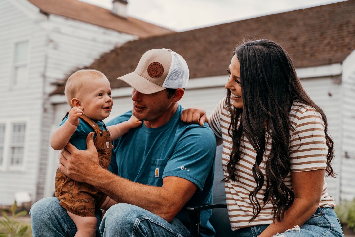 Family enjoying a candid moment together near a white house exterior.