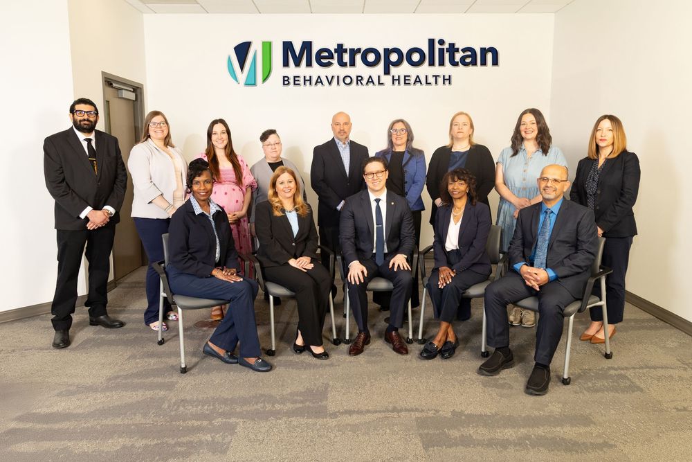 Business professionals seated in formal attire along a hallway for a corporate group photo session.