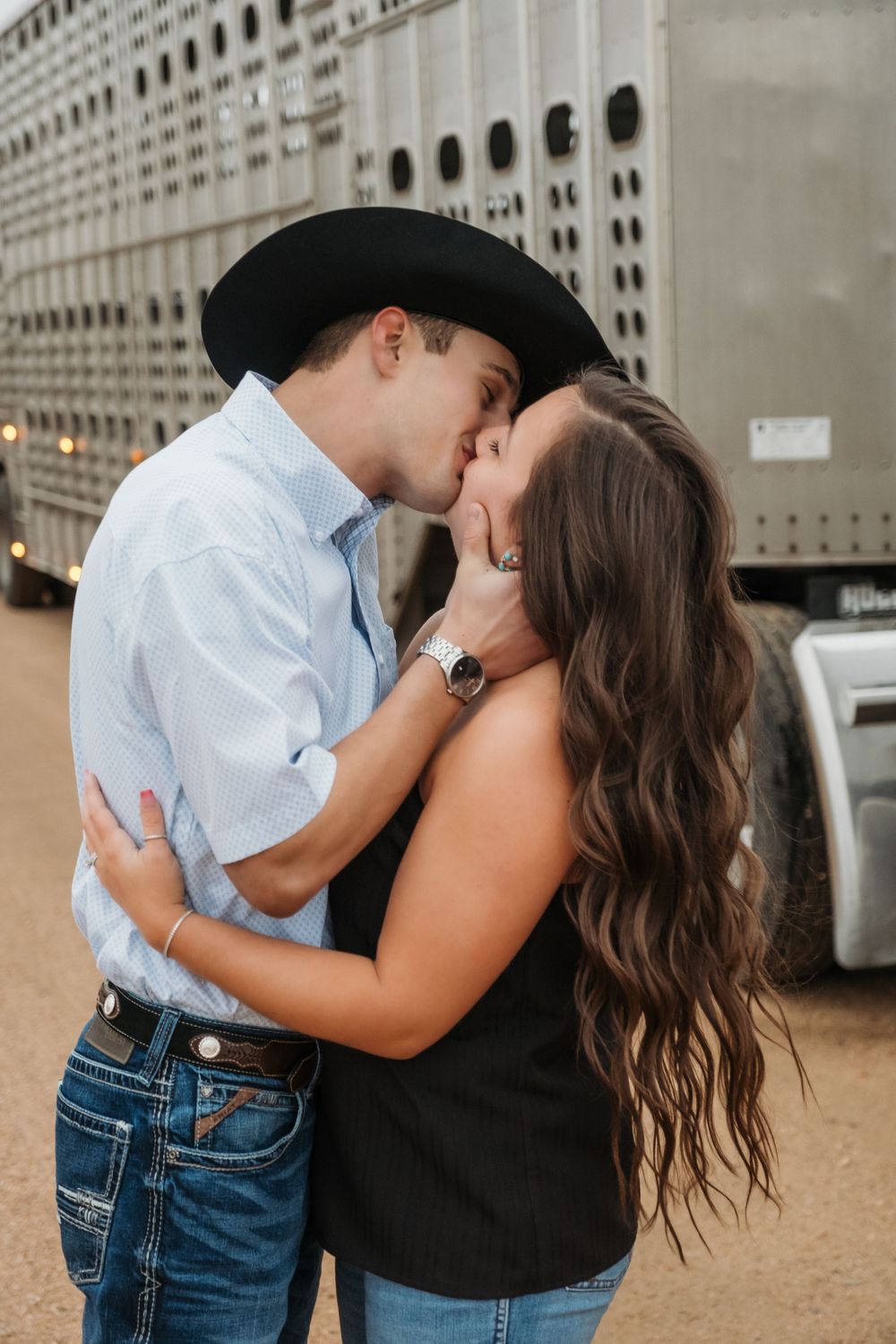 A romantic couple shares multiple passionate kisses while standing outside in front of an urban building.
