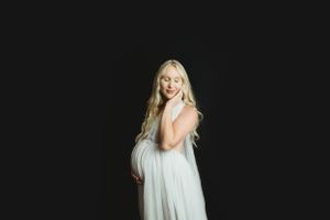 Ethereal white dress portrait against a black background in studio lighting.