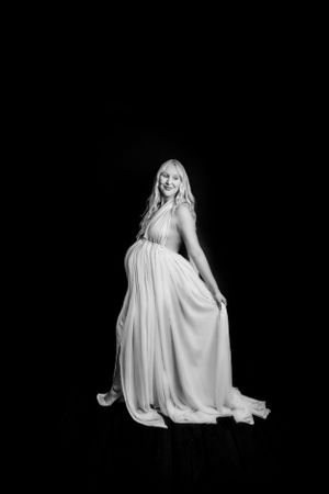 Elegant white flowing dress captured in dramatic studio lighting against black.