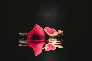 Pink rose petals floating on reflective dark water surface create an artistic composition.