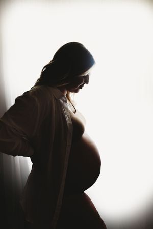 Silhouette maternity portraits capturing pregnancy moments in dramatic lighting.