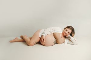 Intimate maternity portrait showing a relaxed pose on a light backdrop.