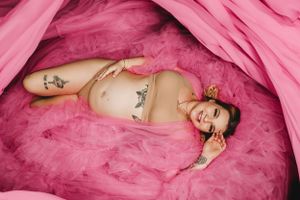 Maternity photo with pink tulle fabric creating a dreamy atmosphere.