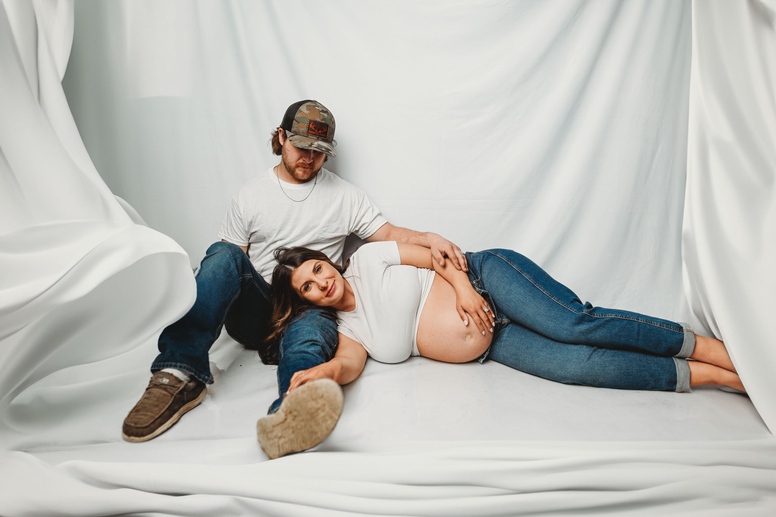 Relaxed family maternity session with natural poses on white background.
