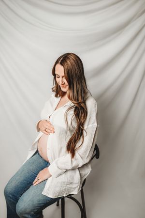Maternity studio portraits against white backdrop showing pregnancy progression.