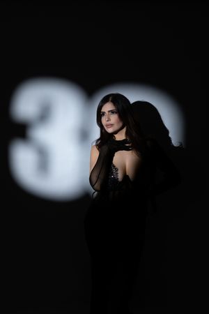 Dramatic portrait with figure in black dress against projected number backdrop.