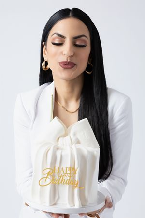 Beautiful birthday cake topped with elegant gold Happy Birthday text against white background.