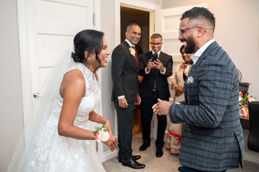 Wedding party sharing a candid moment and laughter in a bright indoor hallway before the ceremony.