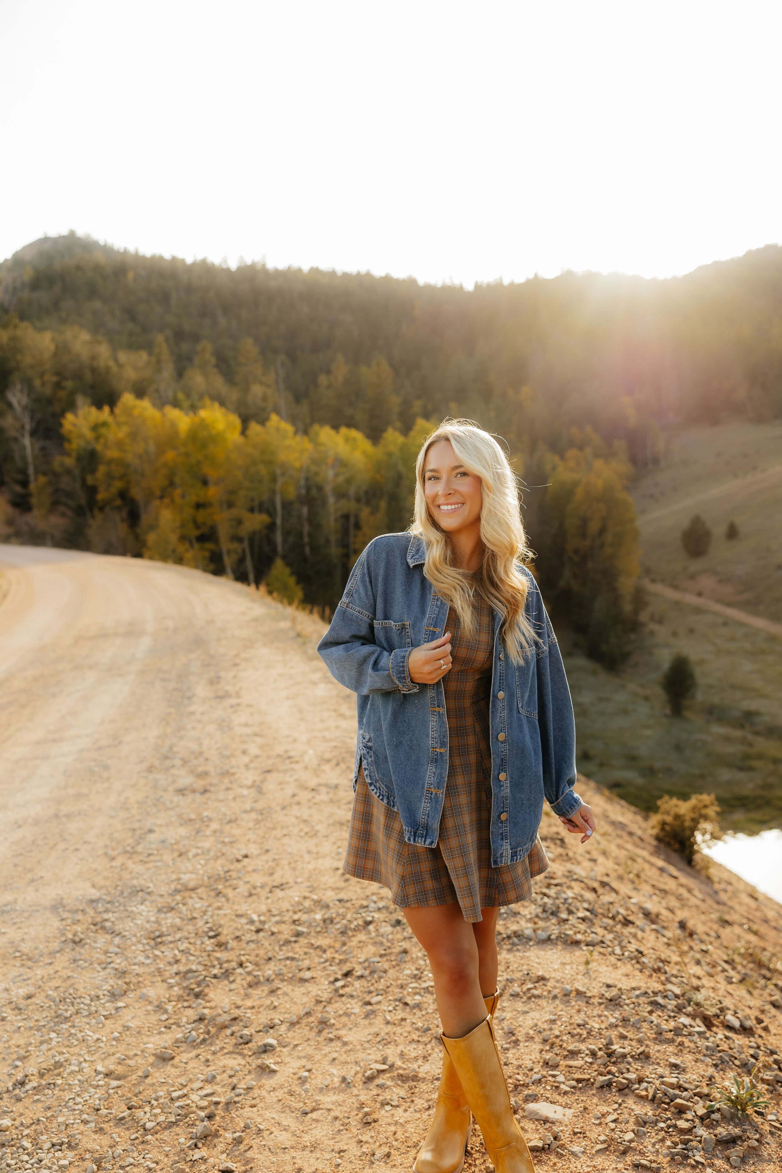 Rustic outdoor portrait session with wooden fence and cowboy boots at sunset.