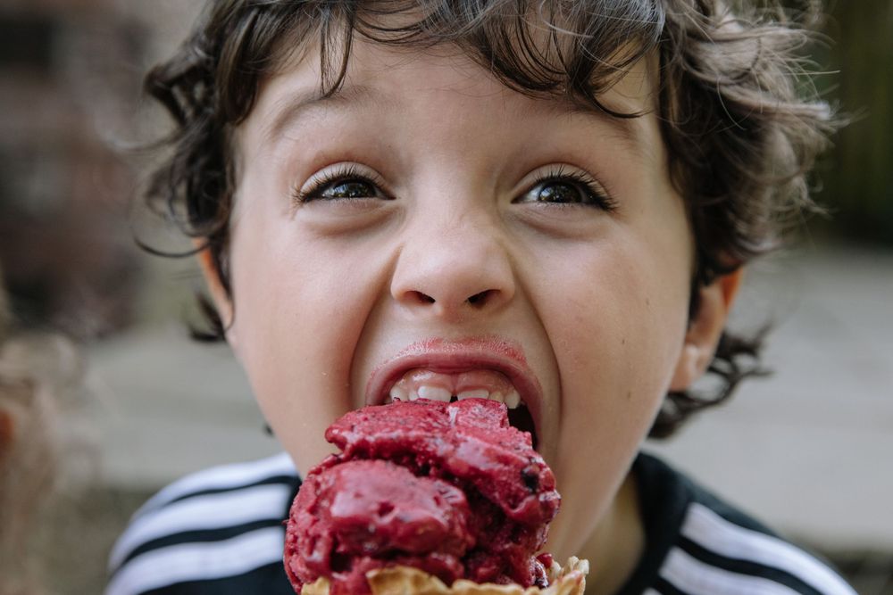 A child enjoying a messy pink ice cream cone with pure delight.