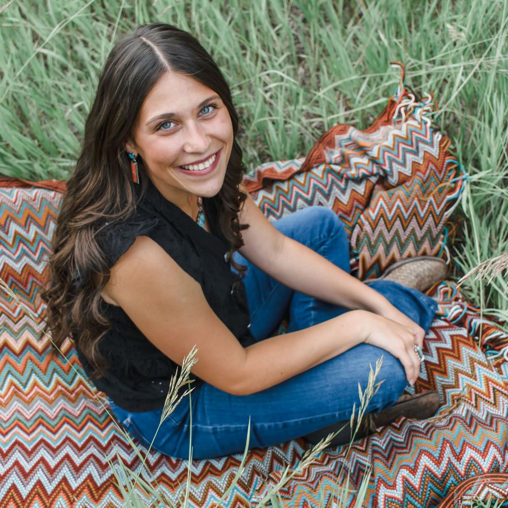 Person lying on chevron patterned blanket in outdoor setting during photo session.