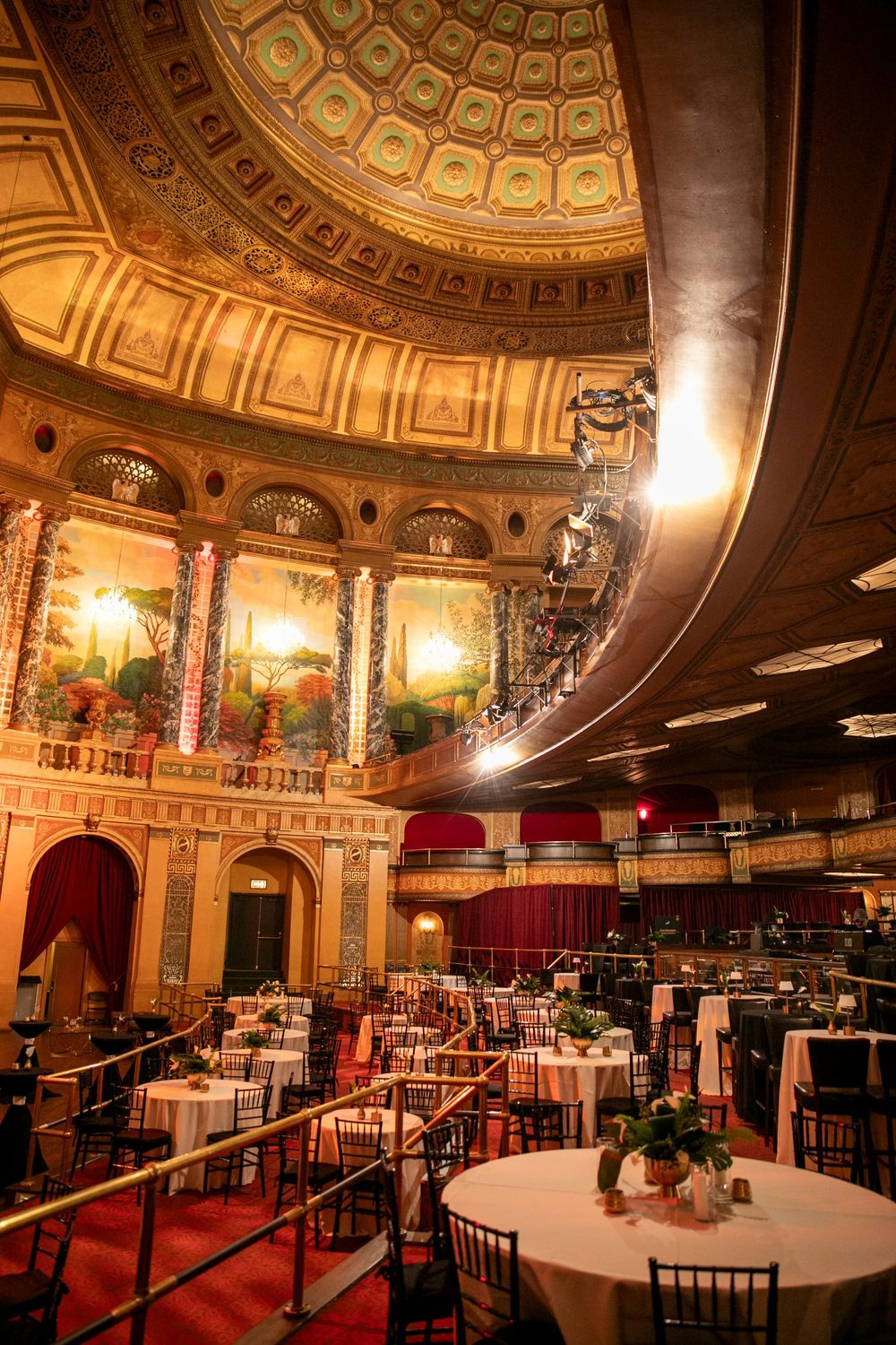 Elegant banquet hall with ornate domed ceiling, murals, and white-clothed tables set for a formal event.