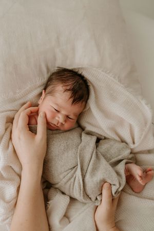 mum touching babys face to sooth during newborn shoot in hamilton nz
