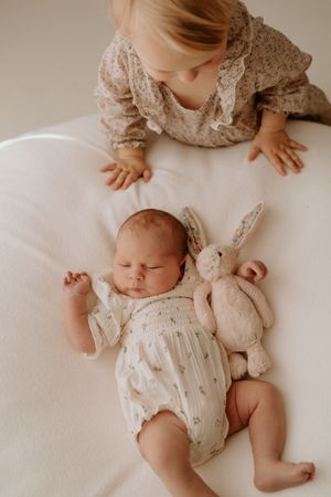 little sister looking at newborn baby sister with teddy at waikato studio