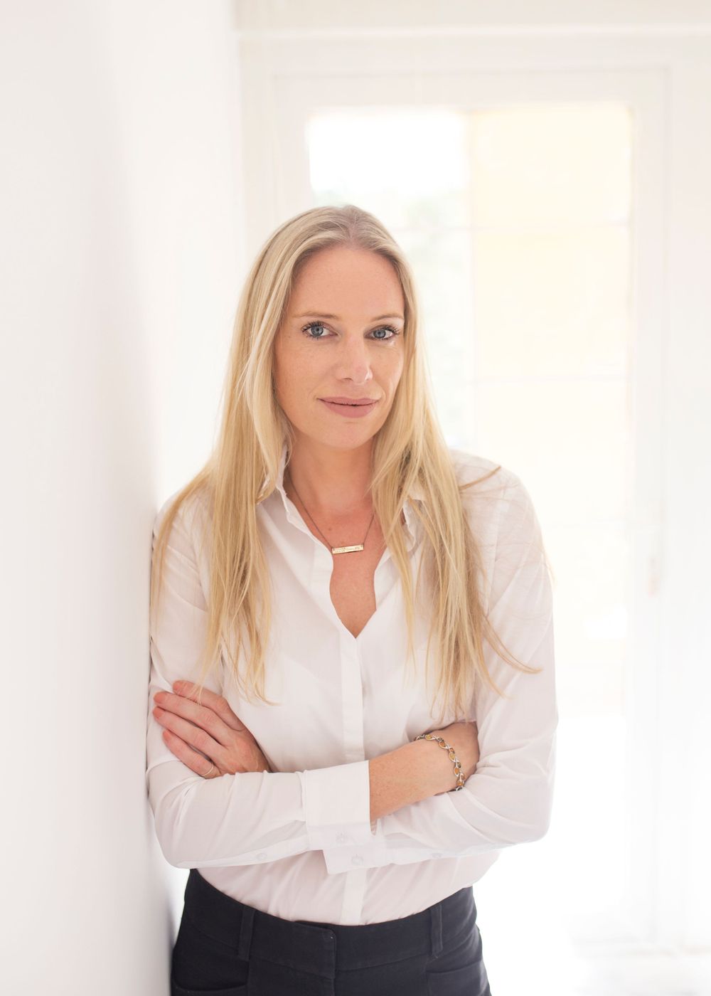 Professional portrait in bright white office setting with modern necklace.