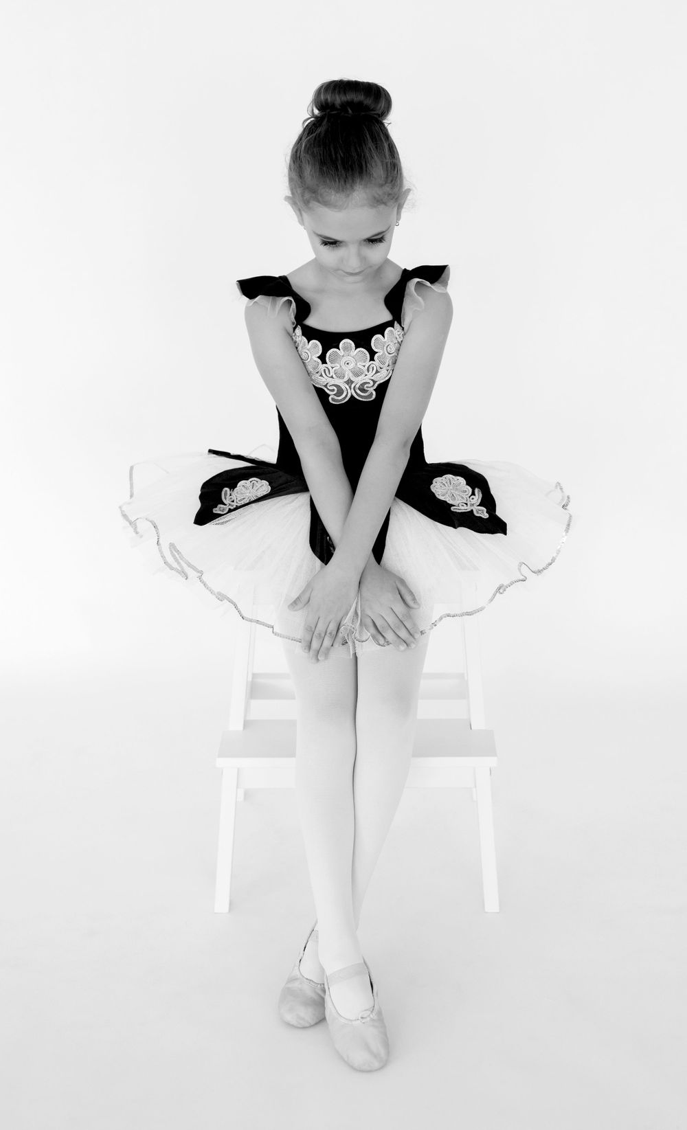 Black and white portrait of ballerina sitting in classic first position.