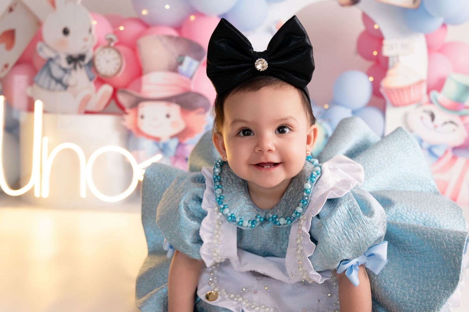 Alice in Wonderland themed baby photoshoot with blue and pink decor elements.