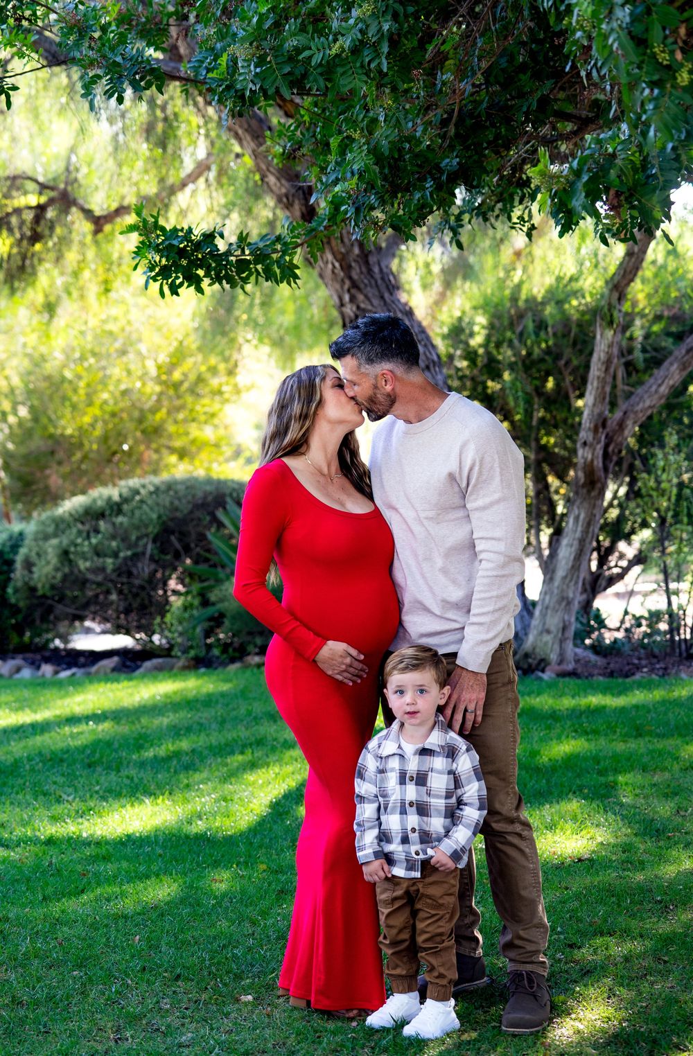 Family maternity photos in a lush garden setting with vibrant greenery.