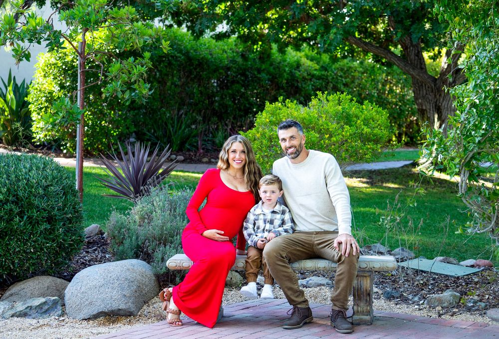 A family poses together on stone steps surrounded by landscaped gardens.