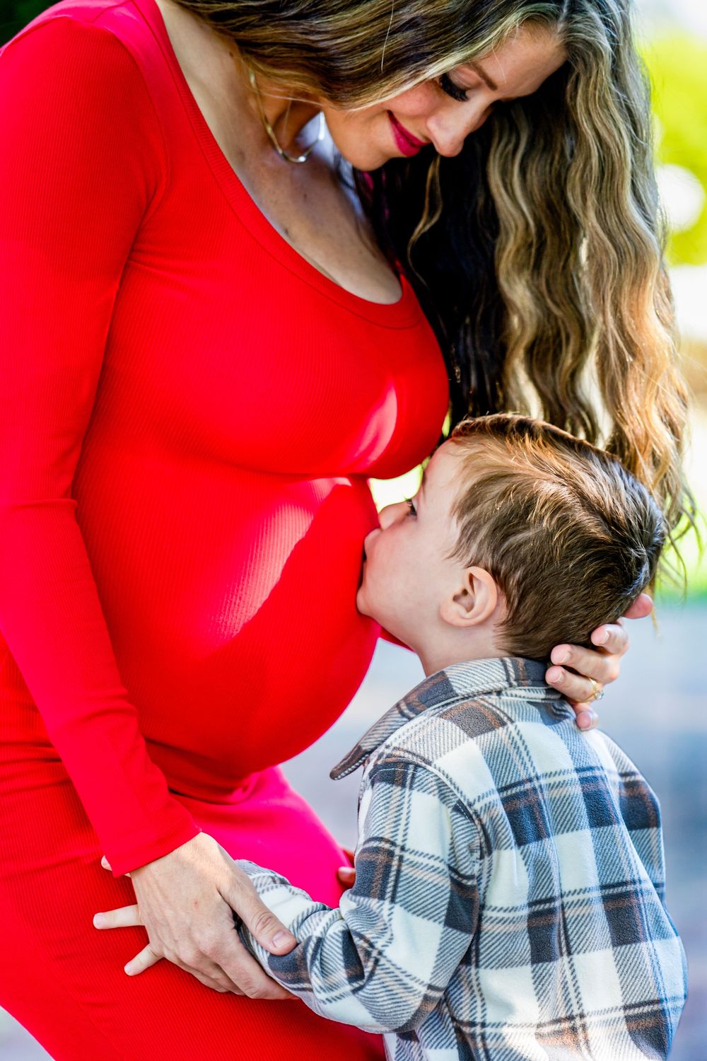 Tender maternity moments captured in close-up shots with a bright red dress.