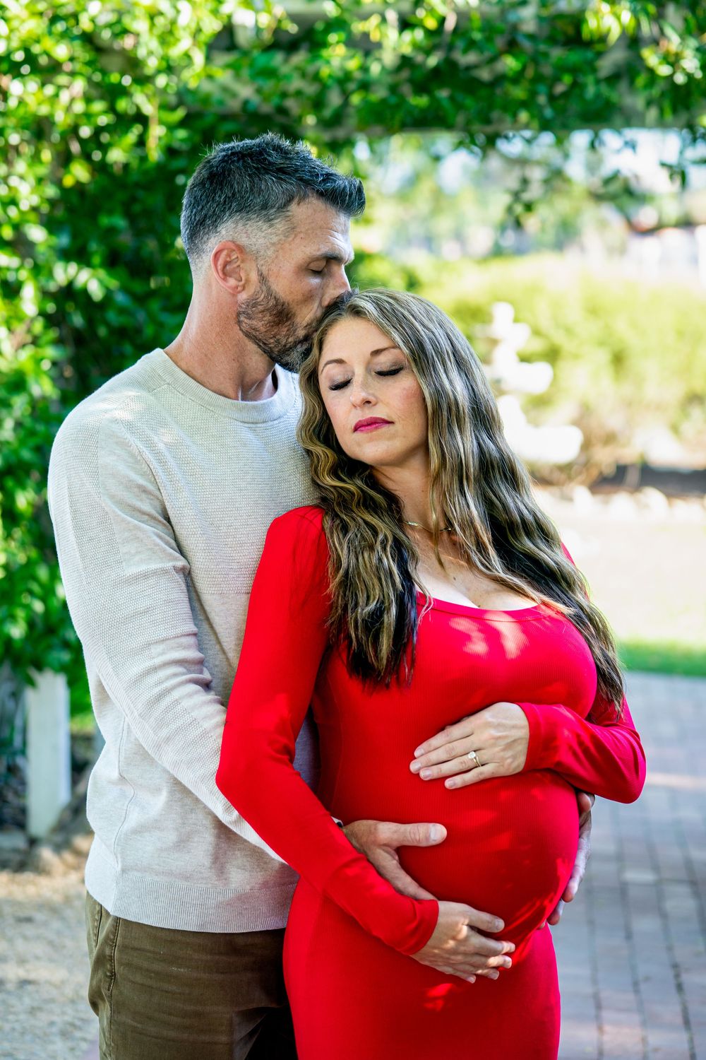 Intimate maternity photos captured on a brick pathway surrounded by greenery.