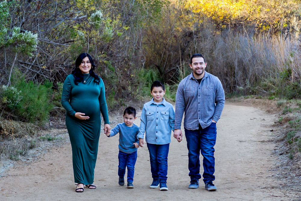 A family of four takes an afternoon stroll together on a dirt path surrounded by autumn foliage.