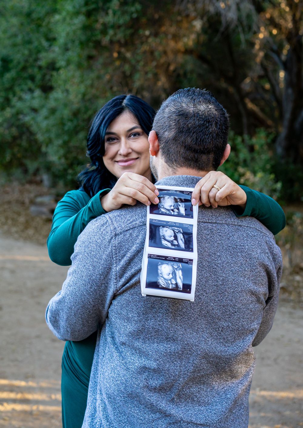 Couple shares joyful pregnancy announcement outdoors holding ultrasound photo strips