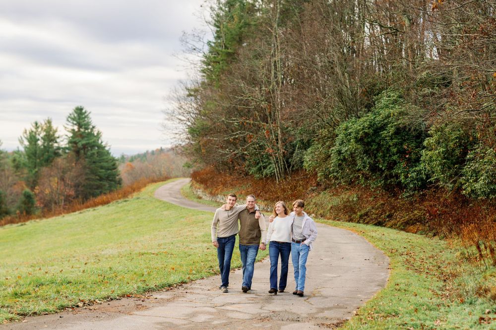 Four friends walking together on a winding path through scenic autumn hills.