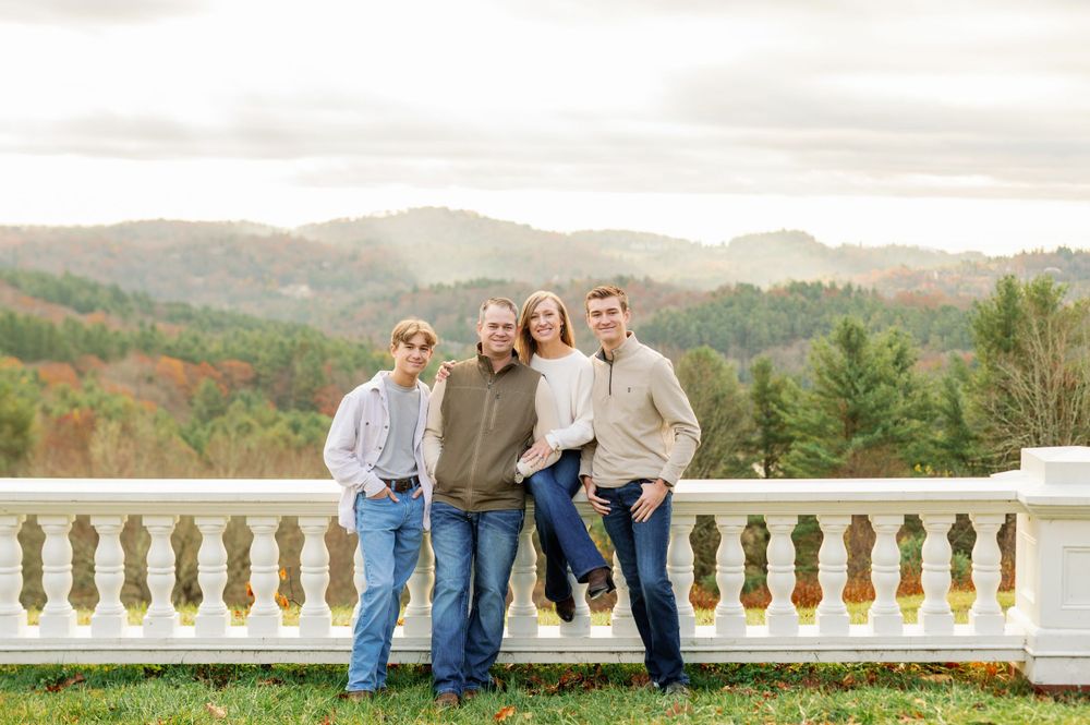 Family group posing on a balcony overlooking mountain vistas.