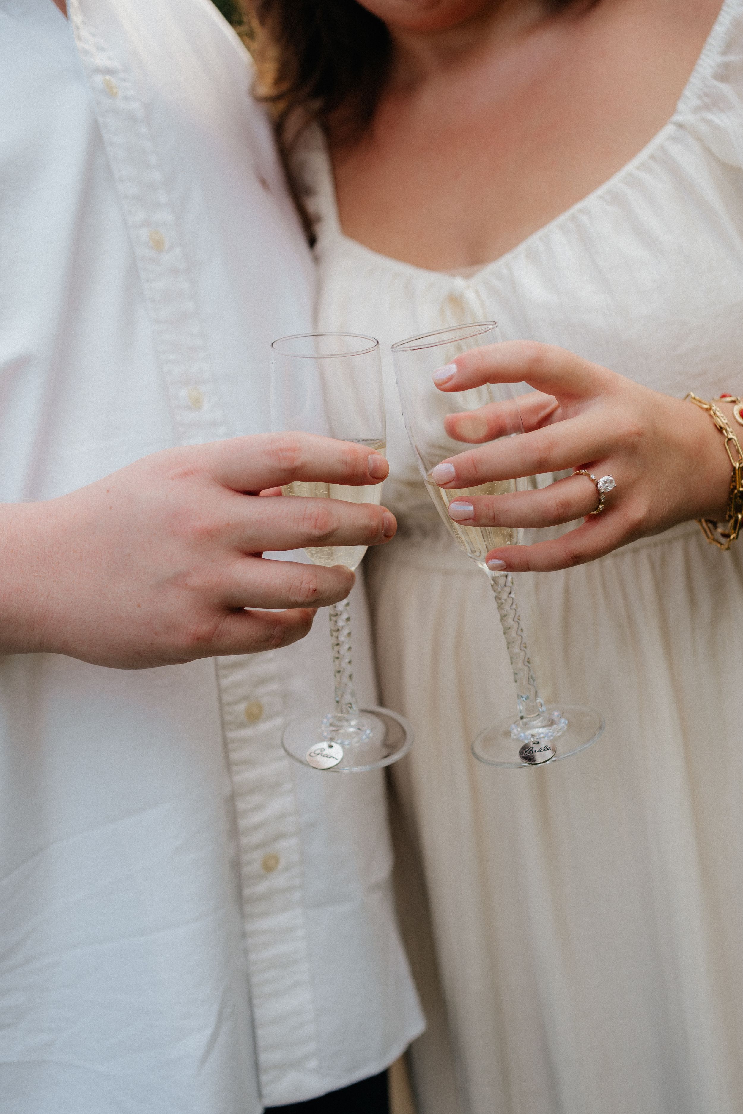 A series of hands holding vintage crystal glasses in white clothing against a light background.
