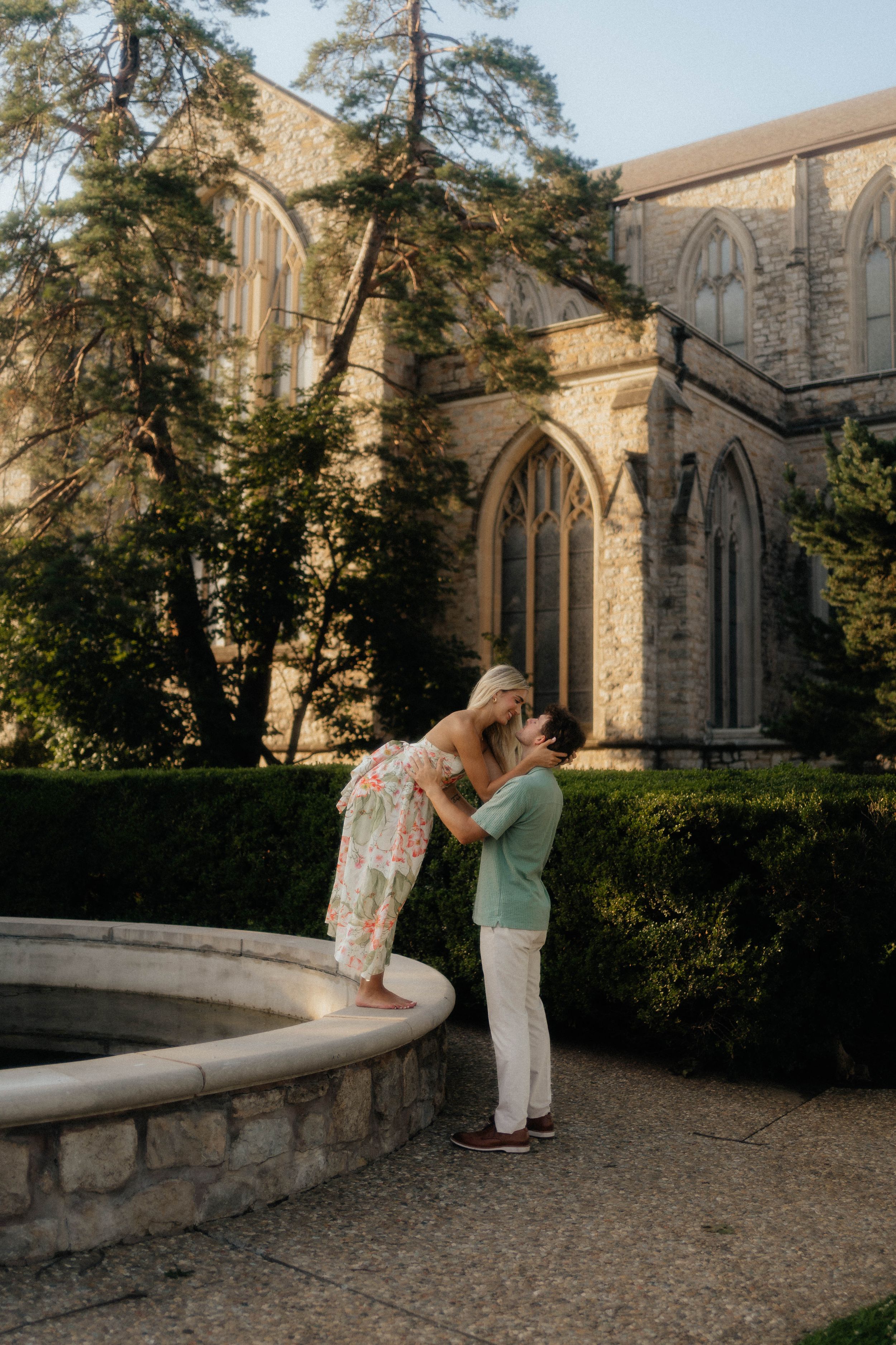A romantic couple shares a tender moment together in front of a historic stone church during sunset.