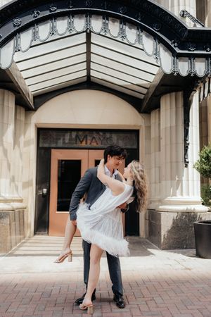 A romantic dip pose sequence beneath an ornate building entrance during a downtown photo session.