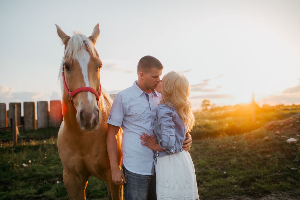 Engaged couple kissing with horses at sunset Zionsville, Indiana