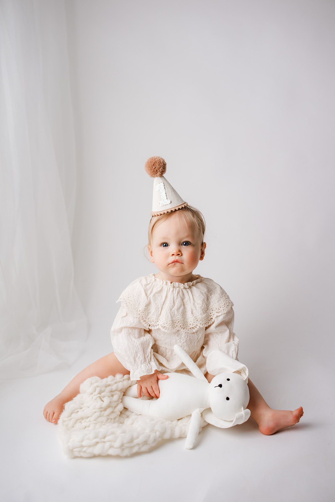 Adorable baby with cake on face sitting in high chair during first birthday cake smash session.