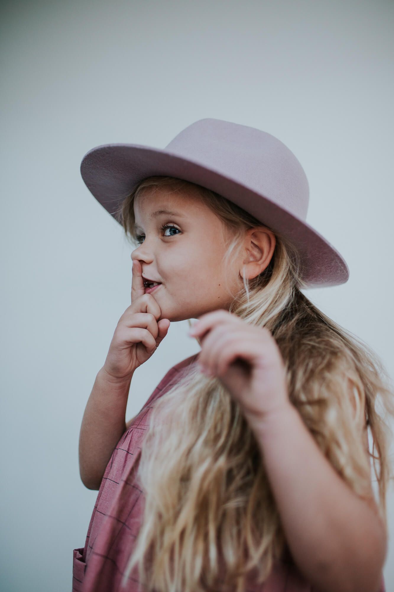 Portrait of a young child wearing a pink wide-brimmed hat.
