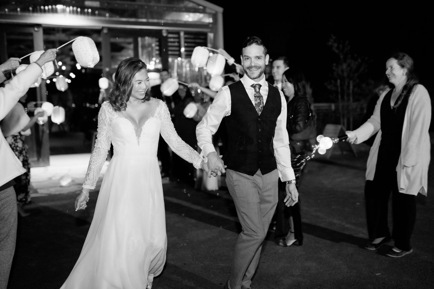 Newlyweds exiting their reception under a tunnel of sparklers at night.