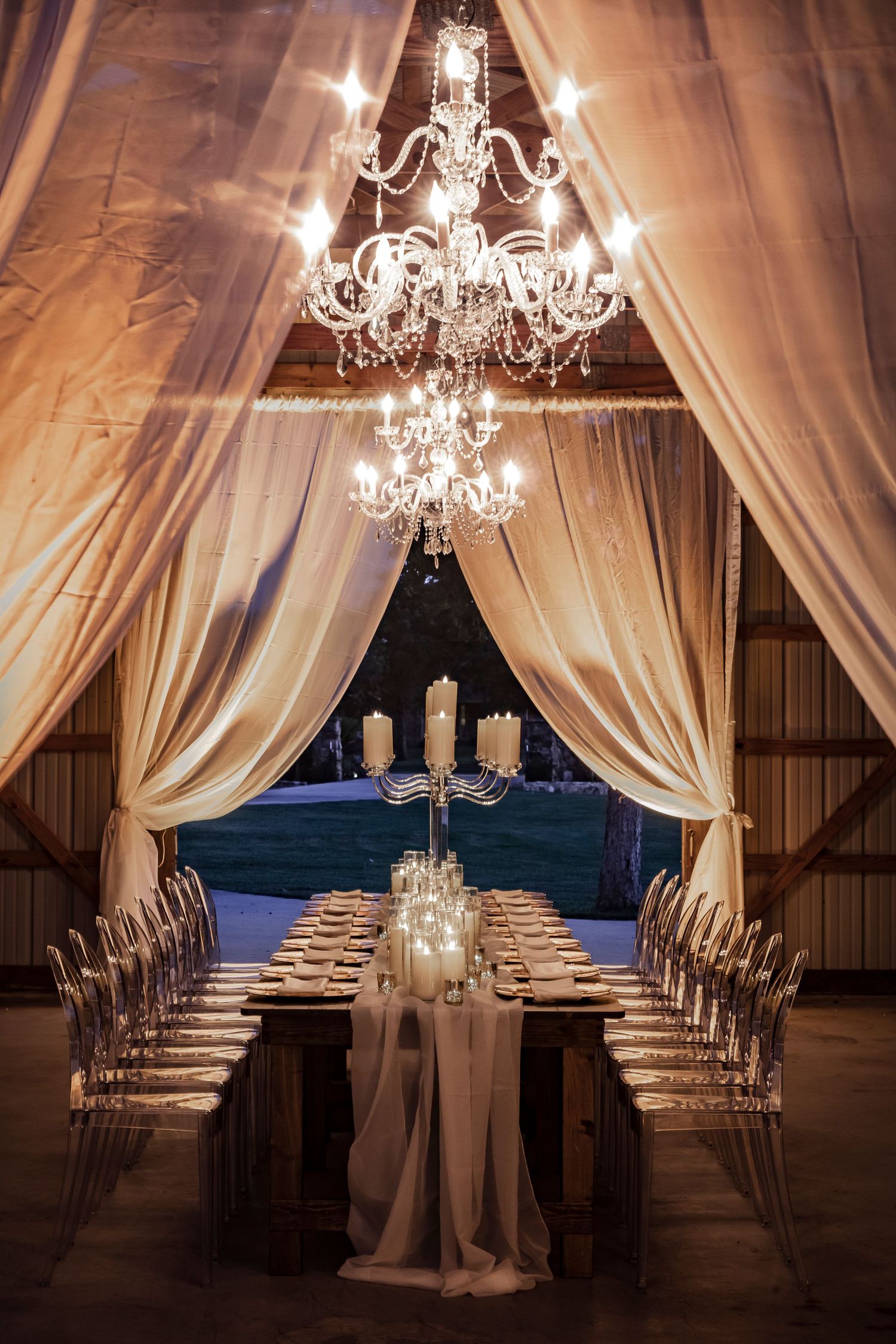 Elegant wedding reception setup with draped fabric, chandeliers and chiavari chairs.