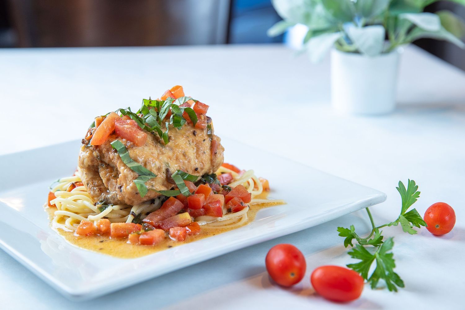 Elegantly plated seafood dish with colorful vegetables and garnishes on white plates.