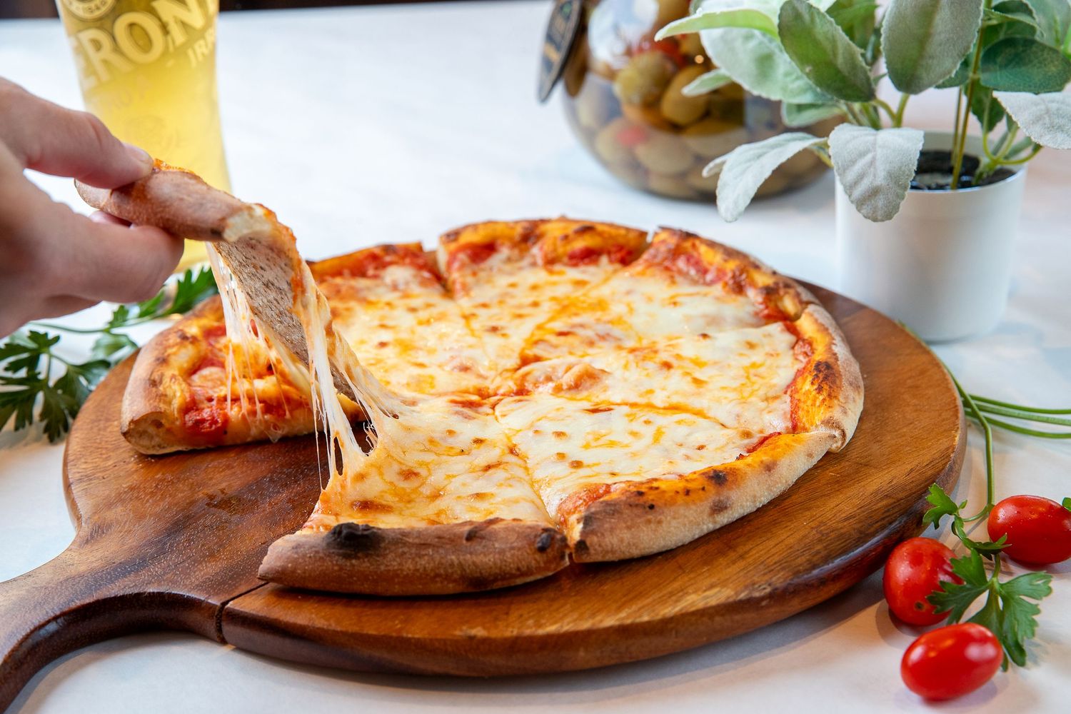 Wood-fired margherita pizza with melted cheese and tomatoes on rustic serving board.